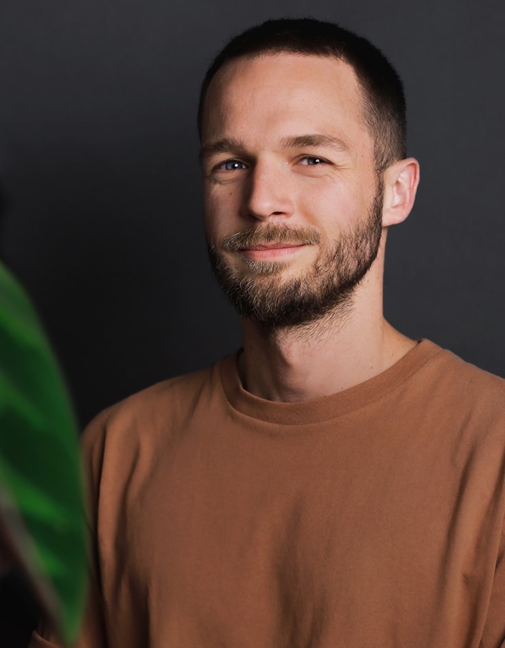 studio nunc team jonas lächelnd in einem braunen Shirt